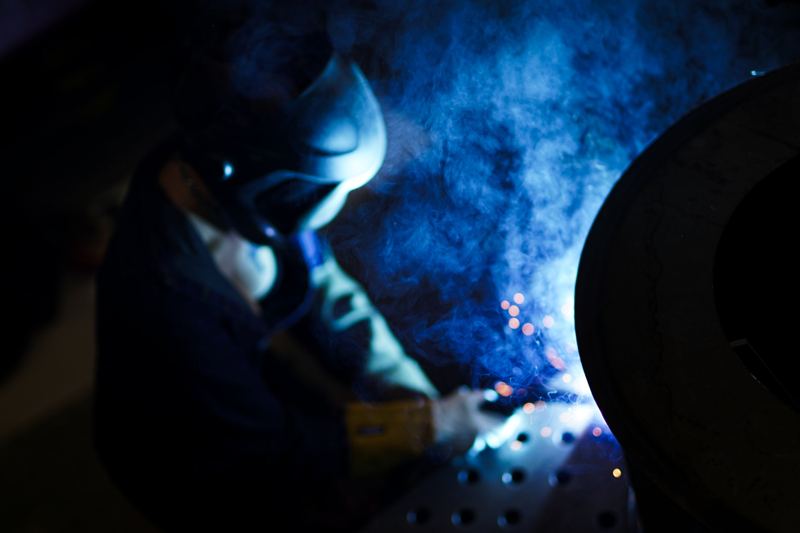Schweisser mit Helm im blauen Licht des Lichtbogens